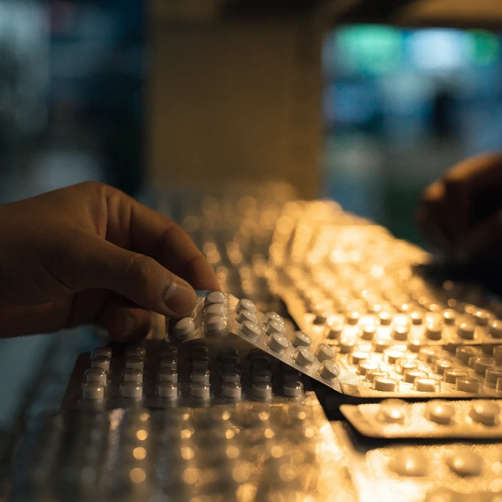 Close macro of unmarked tablets behind a foil blister sealing layer